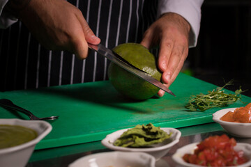 Chef cook preparing salad with salmon and avocado in his kitchen. Freezer food prepare in process vegetarian salad by chef hand in home kitchen. Dark black background with Text area for design menu 