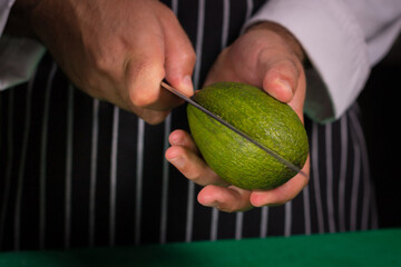 Chef cook preparing salad with salmon and avocado in his kitchen. Freezer food prepare in process vegetarian salad by chef hand in home kitchen. Dark black background with Text area for design menu 