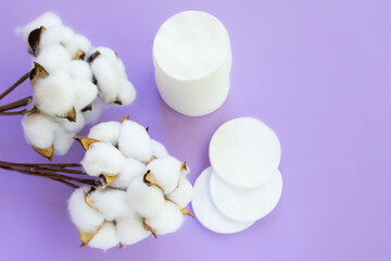 Top view of lots of white round cotton pads on light purple background with opened wool cotton buds.Concept of hypoallergenic cosmetic accessories