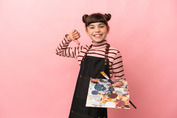 Little artist girl holding a palette isolated on pink background proud and self-satisfied