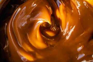 closeup of spoon with dulce de leche on wooden base and dark background typical and traditional sweet from Argentina