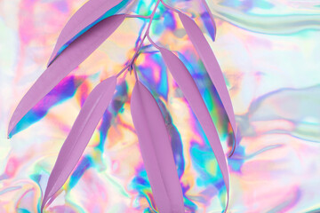 Pink colored leaves of palm against the rainbow colors Holographic foil background. Modern spring concept. Flat lay. Copy space.