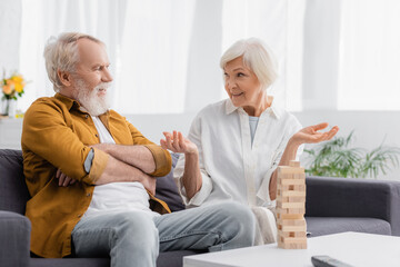 Senior woman talking with husband near blocks wood game on blurred foreground