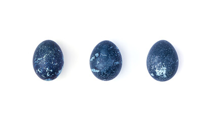 The three eggs are colored with natural dyes with a dark blue color on a white background. The concept of Easter.