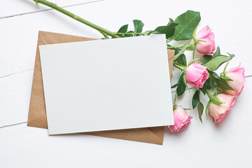 Greeting card mockup with fresh roses on white wooden background