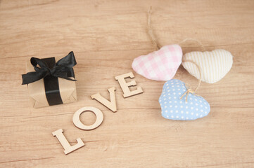 word Love from wooden letters with colorful fabric hearts on a wood background. Happy Valentines Day