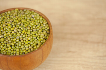 Mung bean, green moong dal in wooden bowl. Copy space. Wooden background.