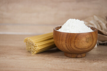 Spaghetti pasta with flour in wood bowi on wooden table