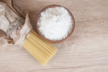 Spaghetti pasta with flour in wood bowi on wooden table