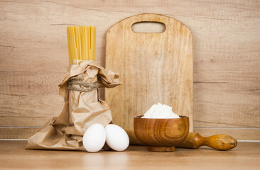 Fototapeta na wymiar Spaghetti pasta dought with eggs, flour and rolling pin on wooden table