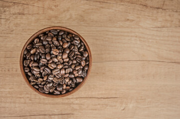 coffee beans in a wooden bowl on a wooden table background