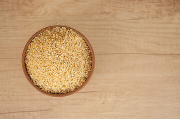 wheat groats in a wooden bowl on a wooden table background
