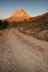 Montaña iluminada por el sol al amanecer, al final de un camino de tierra. El Almorchón, Cieza (Murcia-España).