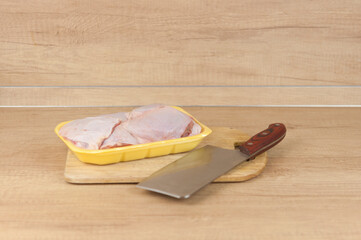 Raw chicken leg on cutting board on wooden background.