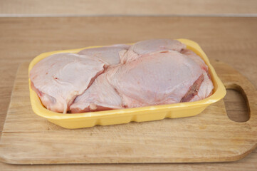 Raw chicken leg on cutting board on wooden background.