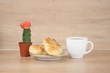 Two bun with poppy seeds with coffee cup on wood table. Breakfast. Good Morning
