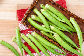 green okras on top of a basket and a red towel
