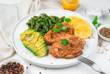 Fried chicken breast, avocado, beans and lemon on a light background. Side view, horizontal. Healthy food.