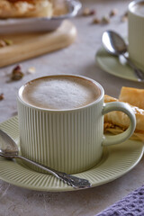 Fragrant cappuccino coffee with puff tubes with meringue and pistachios close-up