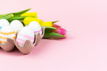 Easter painted eggs with tulips on a pink background. Copy space. Easter celebration concept.