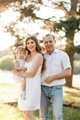 Fototapeta premium Family enjoying life together in the summer park. People having fun in nature. Happy young family outdoors. Mother, father, child of three smiling while spending free time outdoors