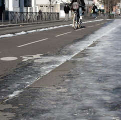 female silhouette riding a bicycle on icy winter bike lanes