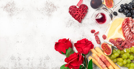 Valentines Day background with appetizers on table italian antipasto snacks and wine. Grape, figs, cheese, bread, prosciutto, meat snaks. Antipasti, gourmet, romantic concept. Copy space. .