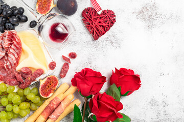 Valentines Day background with appetizers on table italian antipasto snacks and wine. Grape, figs, cheese, bread, prosciutto, meat snaks. Antipasti, gourmet, romantic concept. Copy space. .