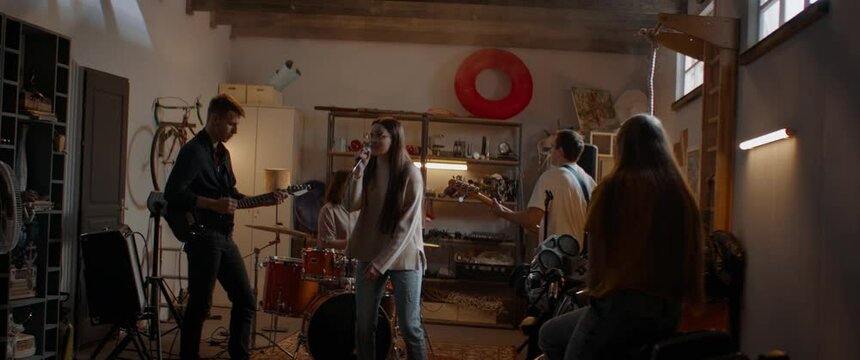 HANDHELD Members of teenager music band having rehearsal inside home garage. Shot with 2x anamorphic lens