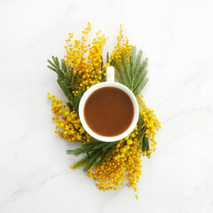 Cup of white coffee with yeallow mimosa flowers. Flat lay, top view.