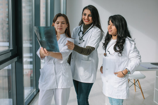 Three women doctors of different races analyze the X-ray