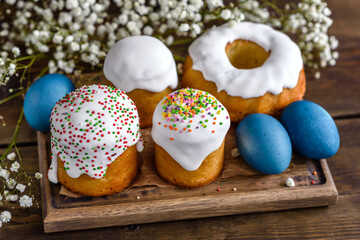 Festive cakes with white glaze, nuts and raisins with Easter eggs on the festive table