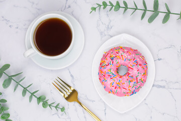 Cup of black coffee with pink donut on the white marble background