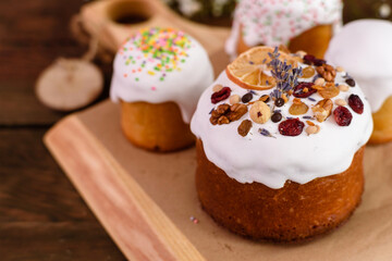 Festive cakes with white glaze, nuts and raisins with Easter eggs on the festive table