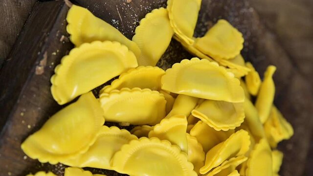 Small ravioli with cheese or meat to cook in broth, a traditional dish for celebrations in italy, Emilia Romagna region. Fresh homemade pasta with filling on a wooden table. vertical 