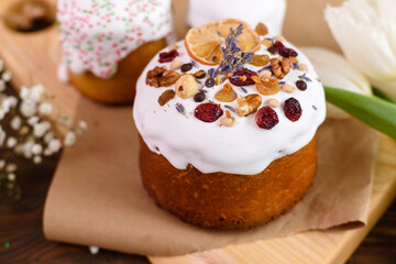 Festive cakes with white glaze, nuts and raisins with Easter eggs on the festive table