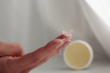 Closeup of a person applying vaseline (petroleum jelly). Concept of slugging - Korean skin care...