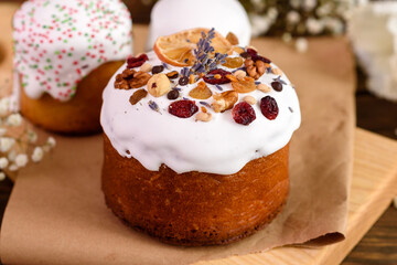 Festive cakes with white glaze, nuts and raisins with Easter eggs on the festive table