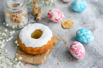 Festive cakes with white glaze, nuts and raisins with Easter eggs on the festive table