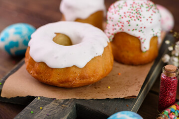 Festive cakes with white glaze, nuts and raisins with Easter eggs on the festive table