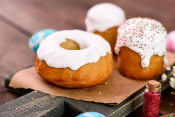Festive cakes with white glaze, nuts and raisins with Easter eggs on the festive table