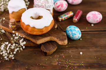 Festive cakes with white glaze, nuts and raisins with Easter eggs on the festive table
