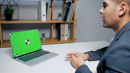Laptop with chroma key near businessman on blurred foreground in office