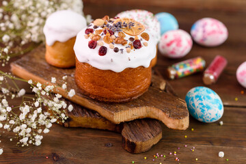Festive cakes with white glaze, nuts and raisins with Easter eggs on the festive table