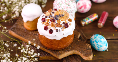 Festive cakes with white glaze, nuts and raisins with Easter eggs on the festive table