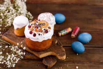 Fototapeta na wymiar Festive cakes with white glaze, nuts and raisins with Easter eggs on the festive table
