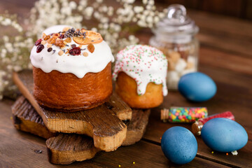 Festive cakes with white glaze, nuts and raisins with Easter eggs on the festive table