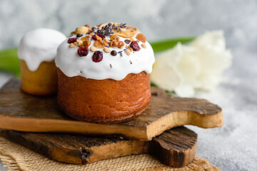 Festive cakes with white glaze, nuts and raisins with Easter eggs on the festive table