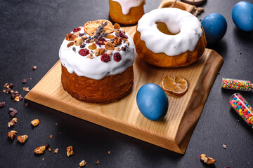 Festive cakes with white glaze, nuts and raisins with Easter eggs on the festive table