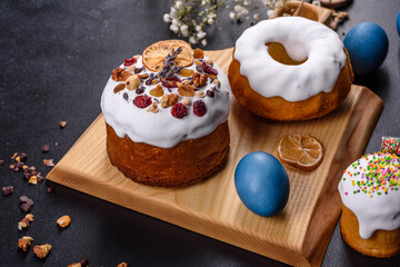 Festive cakes with white glaze, nuts and raisins with Easter eggs on the festive table